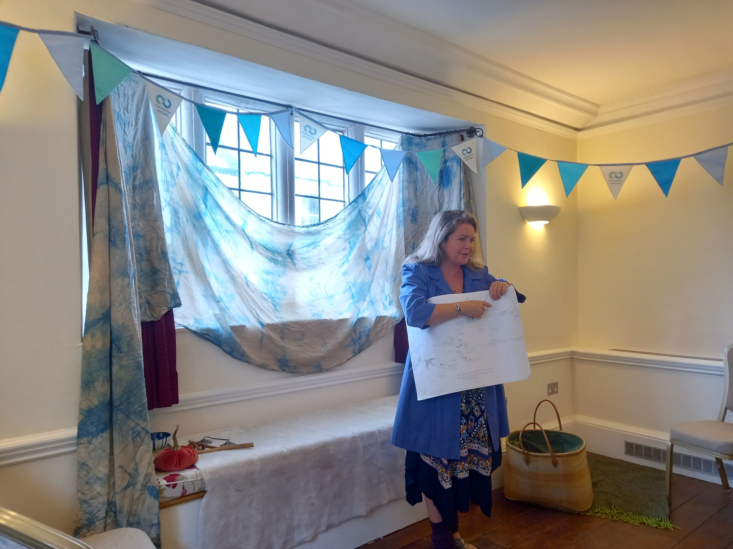 Clare Viner standing in a room decorate with bunting and telling a story.