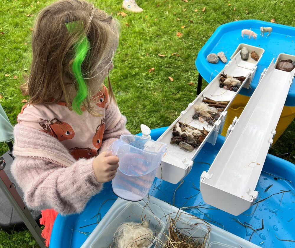 Child pouring water down a pipe filled with a variety of obstacles.